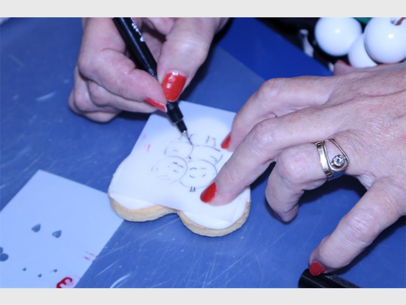 a woman traces a picture onto a cookie
