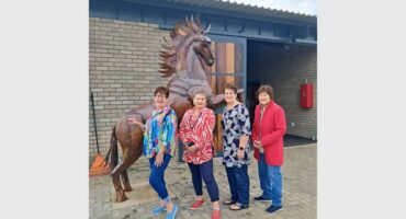 four women in front of a horse stable