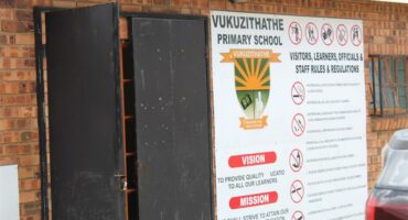 A brick wall with a school's name and emblem