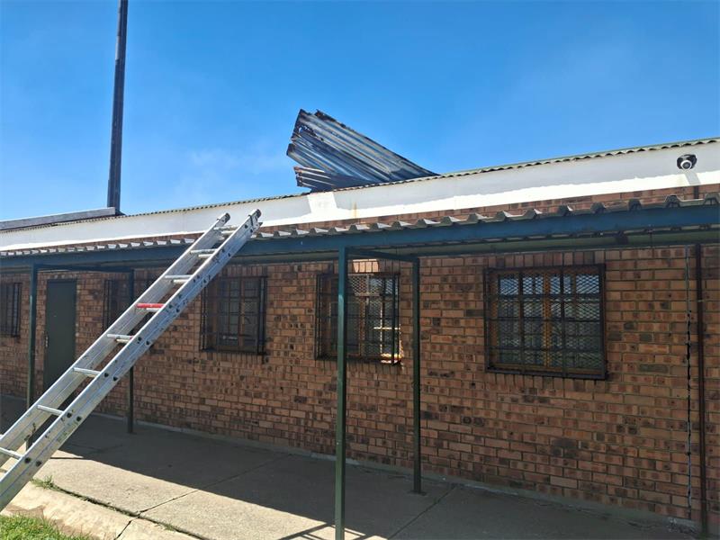 a ladder leads up to the roof of a building where a roof sheet is pulled up.