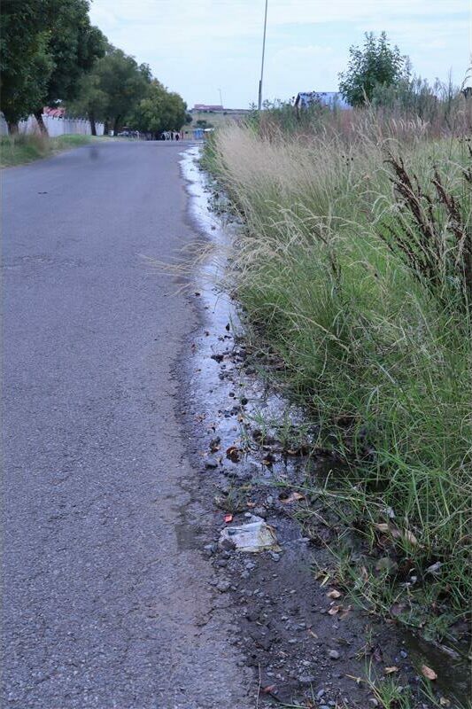 water flows down the side of tar road