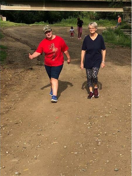 two women walk on dirt road