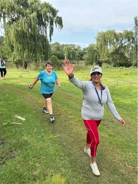 woman waves as she walks in the park