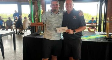 tow men hold up a trophy at a golf club
