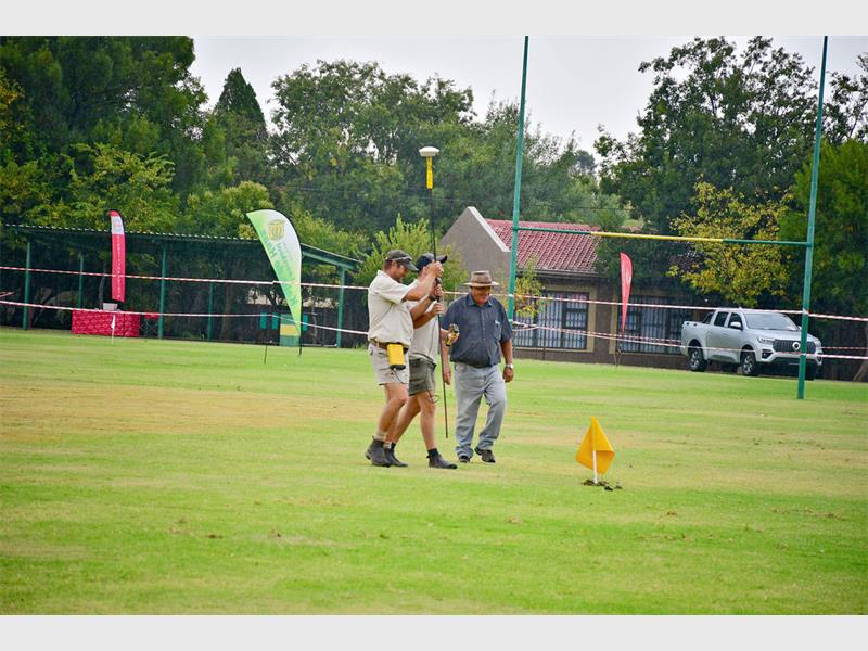 three men mark something on a rugby field