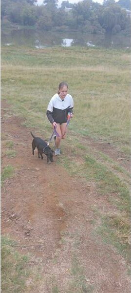 a woman runs uphill with her dog