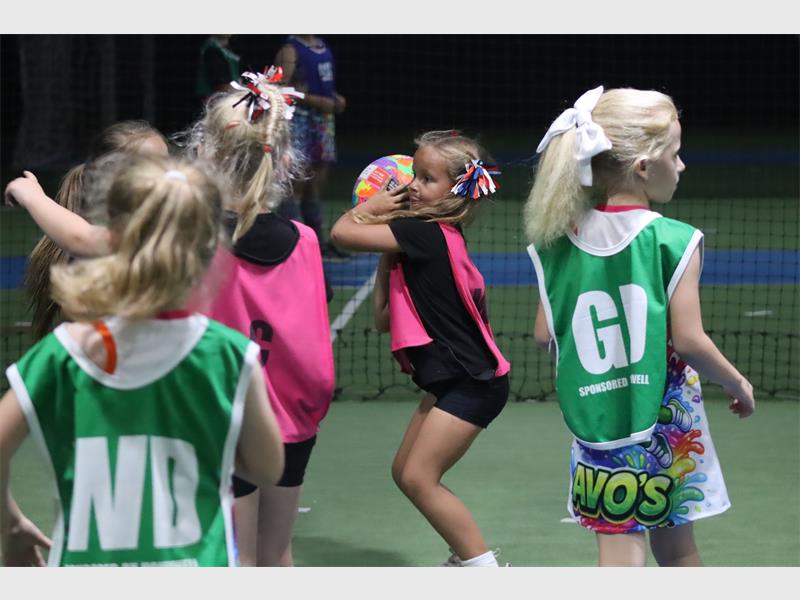 a girl in a pink bib aims the ball