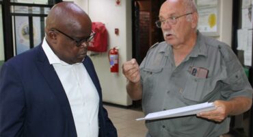 a man in a suit listens to another man talking