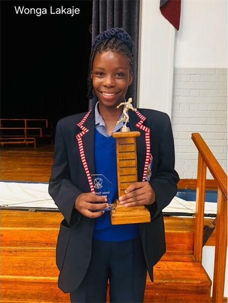 girl wearing a school blazer holds up a trophy