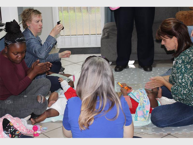 women sit in a circle with babies on the floor