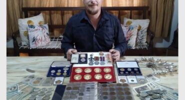 man with a collection of gold coins and medals
