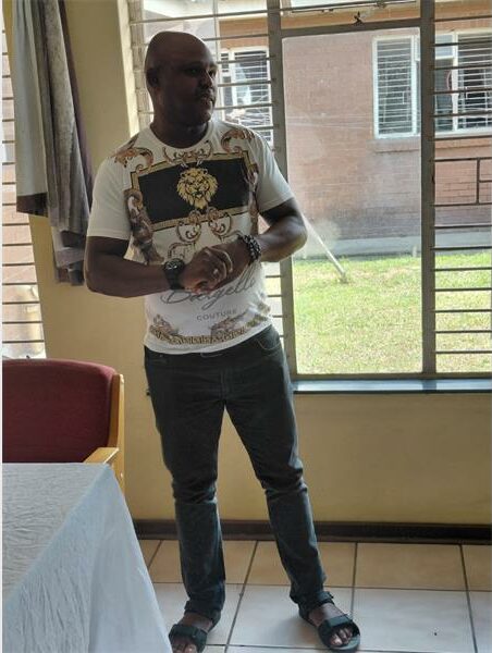 man in jeans and t shirt speak to people in a hall