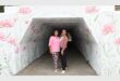 Two women in a tunnel painted white with pink flower