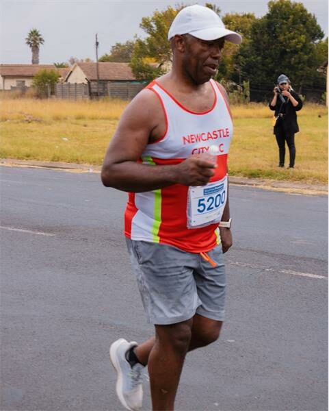 a man wearing a running vest from Newcastle is taking part in a road race