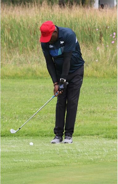 man with red cap and black clothes playing golf