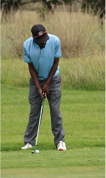 man in light blue shirt and black trousers on the golf course