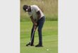 man with white shirt and black pants playing golf