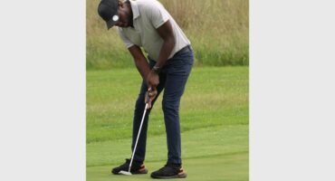 man with white shirt and black pants playing golf