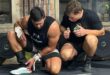 two men in power lifting gear are kneeling down