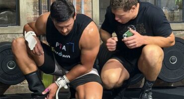 two men in power lifting gear are kneeling down
