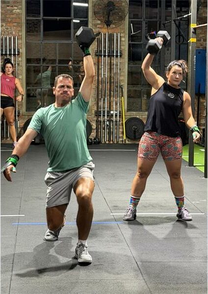 a man and a woman hold weights up high