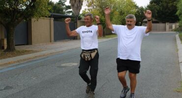 two men in white and black hold their hands in the air