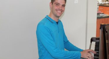 man in a blue shirt plays piano