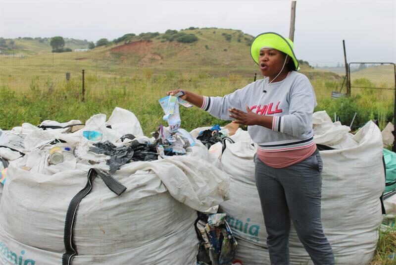 woman stands with big containers filled with recyclables