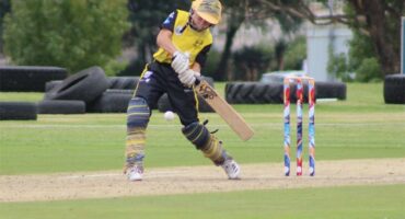 a boy in yellow and black clothes bats in cricket