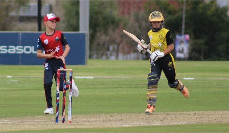 a boy in yellow and black clothes bats in cricket