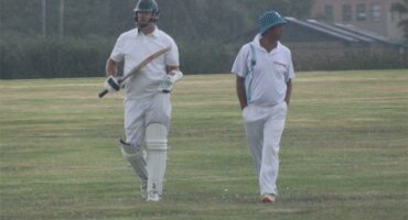 two cricket players walk off the pitch