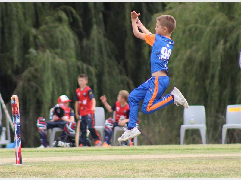 boy in blue and orange cricket clothes bowl