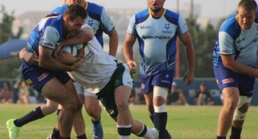 rugby players in blue and white teams mid-tackle