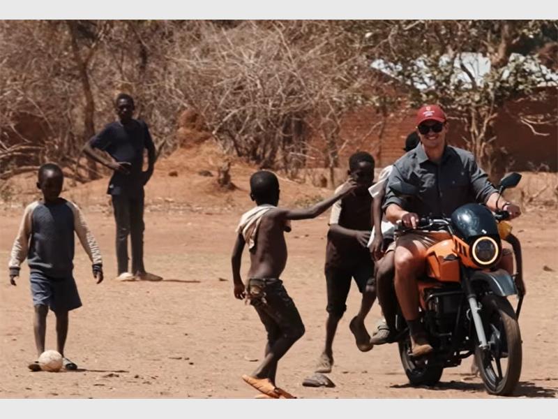 children in Africa run after a man on a motorcycle