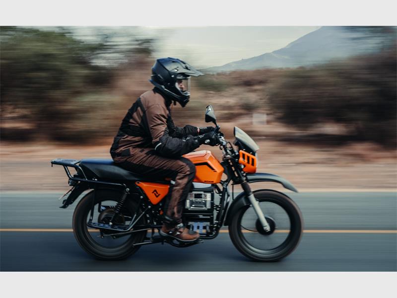 a man riding an orange motorcycle through the countryside
