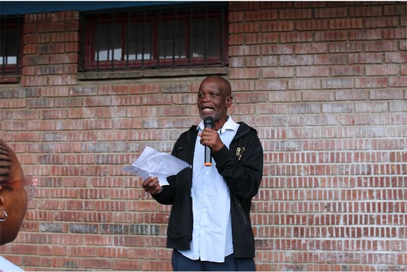 an with a white shirt speaks into a microphone