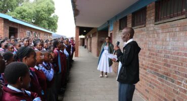 a man stands in front of school children