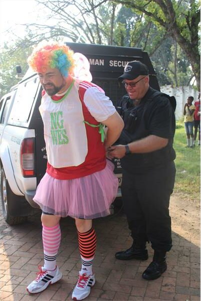 Security guard ties the cuffs to the hands of a a man dressed as a clown