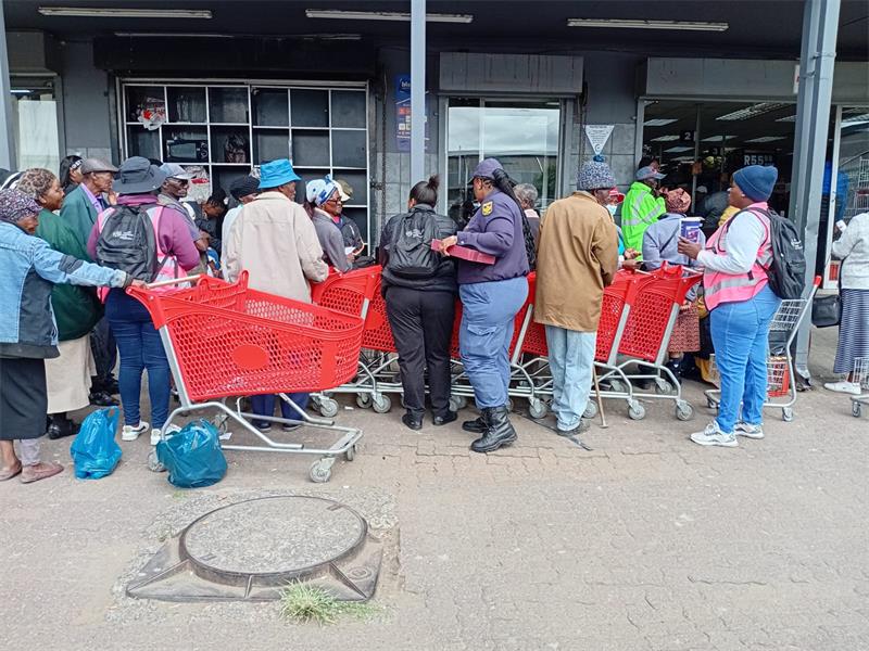 police and volunteers speak to old people in a line with trollies