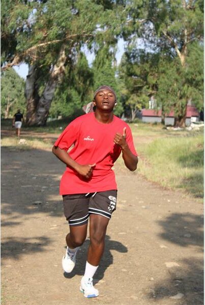 boy in red shirt runs on dirt path