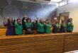 women in black and green standing in the public gallery of a courtroom
