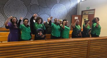 women in black and green standing in the public gallery of a courtroom