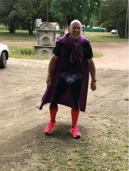 a male athlete with a purple cape and underpants over running shorts