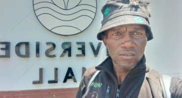 a man with a hat in front of River Side mall's entrance
