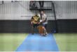 a man gets ready to bat at an indoors cricket game