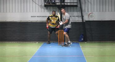 a man gets ready to bat at an indoors cricket game
