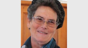 elderly woman with a hat on her head, spectacles and a scarf