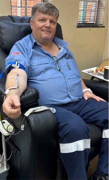 Man donating blood in a medical setting, seated comfortably in a chair with medical equipment nearby.
