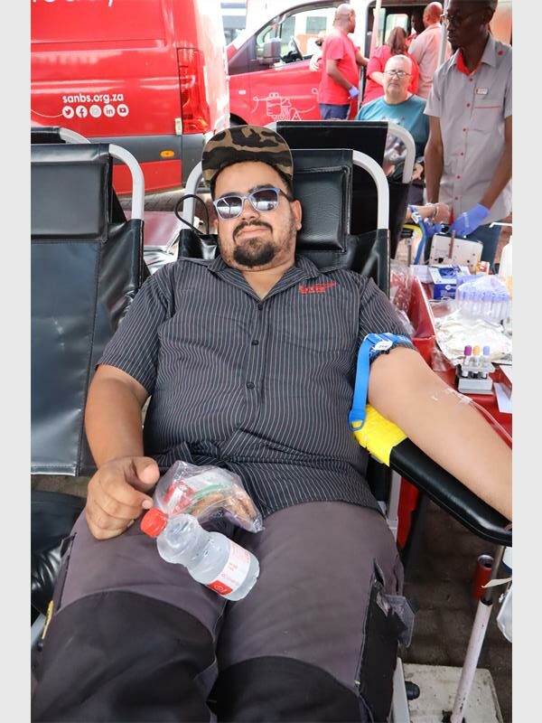 man with sunglasses lies back to donate blood