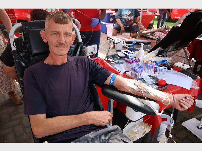 thin elderly man with a moustache donates blood